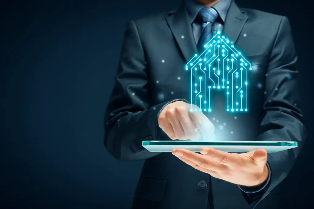 man-in-suit-holding-tablet-with-digital-house-made-of-lights-in-circuit-above-tablet