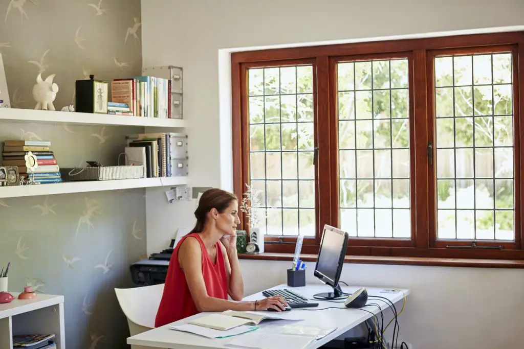 woman-sitting-in-home-office-at-desk-with-monitor-and-landlord-paperwork