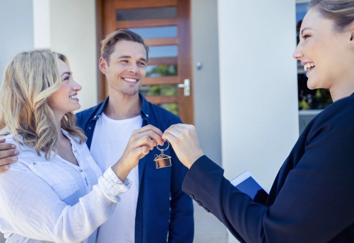 A property manager handing a set of keys to new tenants renting a property.