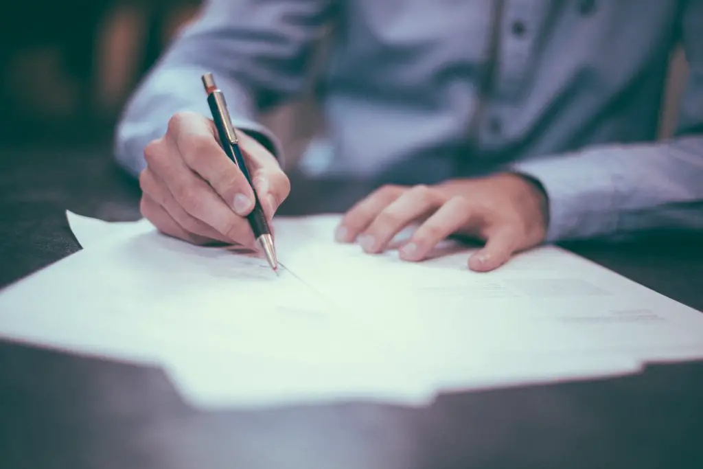 man signing legal documents on desk