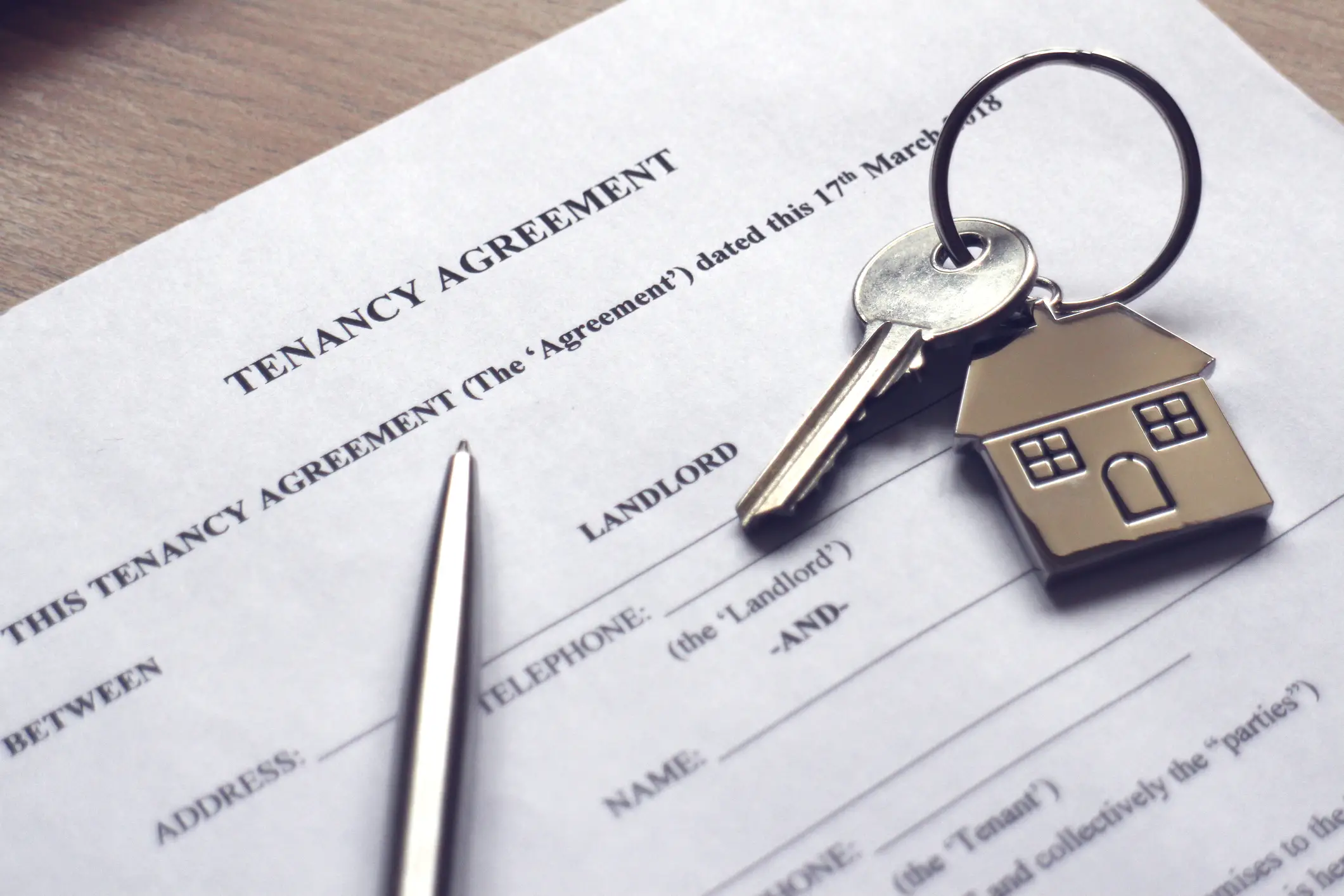 A house key resting on paperwork titled, "Tenant Agreement." RentPrep tenant screening